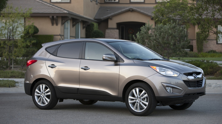 A brown 2011 Hyundai Tucson in front of a house.