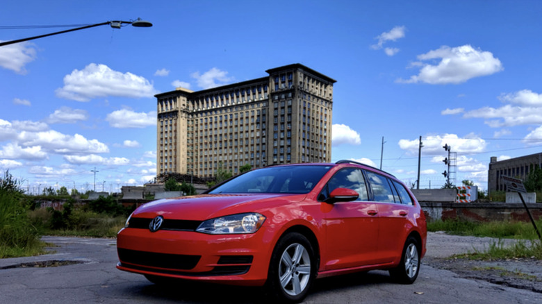 a red 2015 Volkswagen SportWagen parked in front of the Michigan Central train station