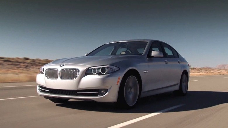 A silver bmw 5 series 550i driving on a track