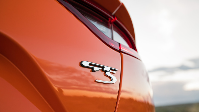 An orange 2019 Kia Stinger GTS shows off its GTS badge in a closeup shot