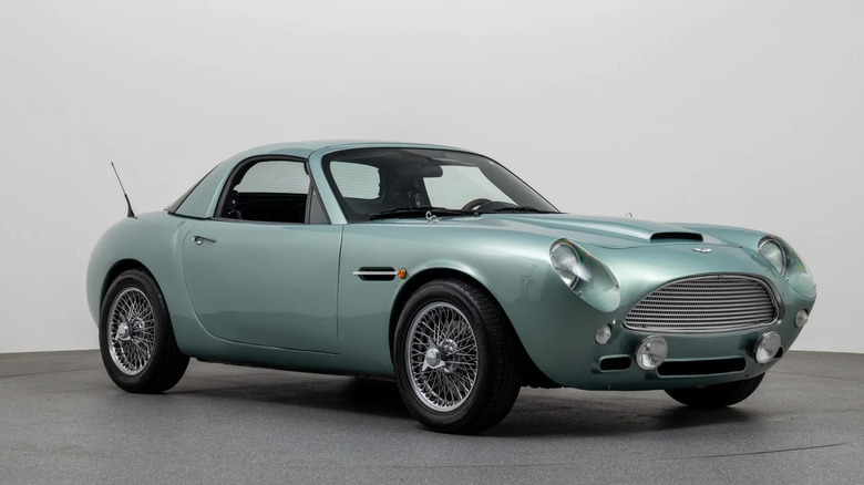 A front three quarters shot of the green Miata with the Aston bodywork with the hardtop fitted in a studio