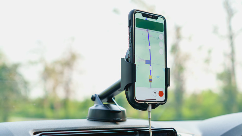 A phone displaying a navigation app in a holder mounted to a car dashboard