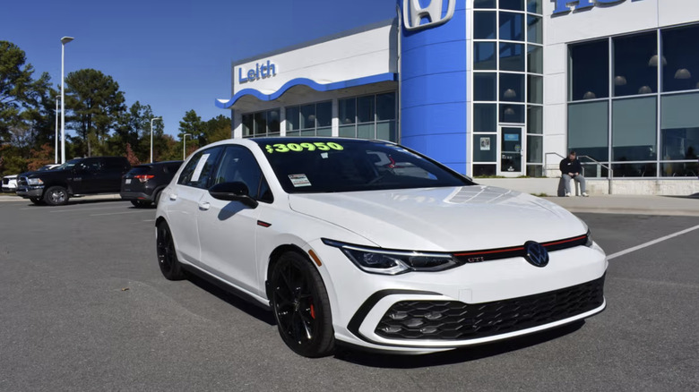 a white volkswagen GTI parked in a dealership parking lot