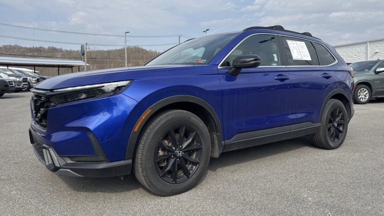 A blue 2024 Honda CR-V Hybrid parked in a used car parking lot