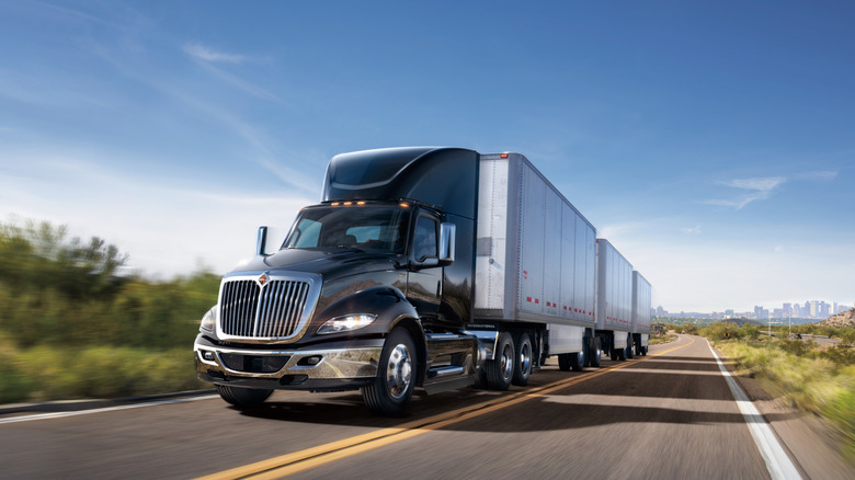 An International RH semi truck pulling three trailers on road
