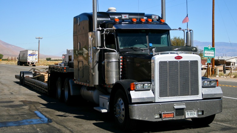 A black Peterbilt semi truck hauling wooden boards