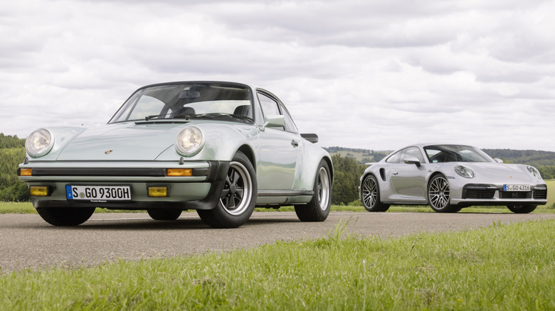 A Porsche 930 and 992 Turbo parked together on an asphalt strip in a field.