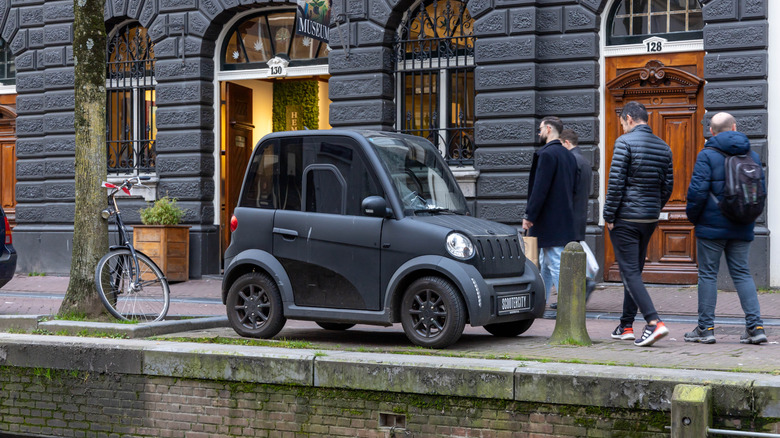 Microcar parked on sidewalk in Amsterdam near canal