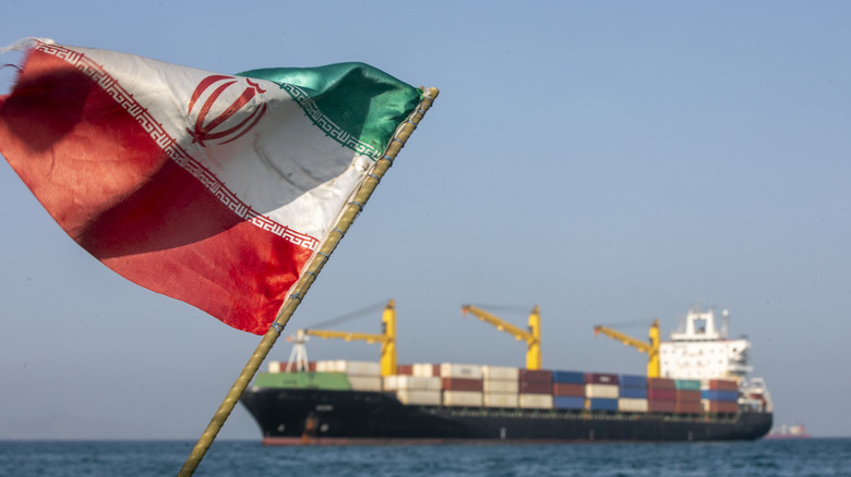 An Iranian flag with a cargo ship in the Strait of Hormuz