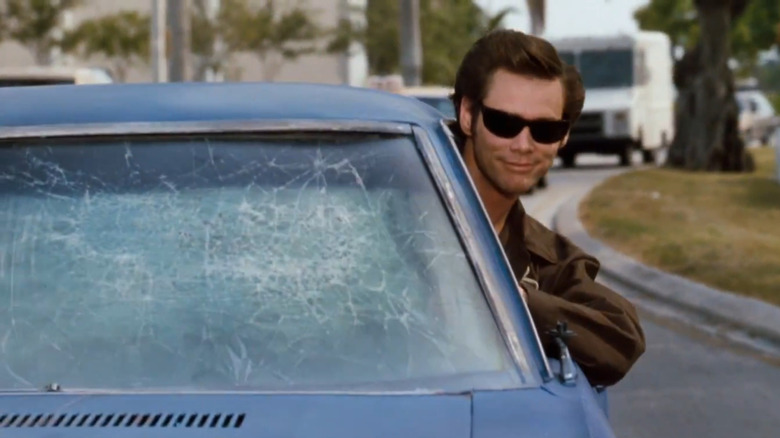 Jim Carrey as Ace Ventura driving his 1970s Chevy Monte Carlo with a broken windshield, leaning out the window while wearing sunglasses