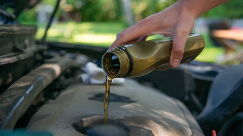 Mechanic adding oil to a car's engine