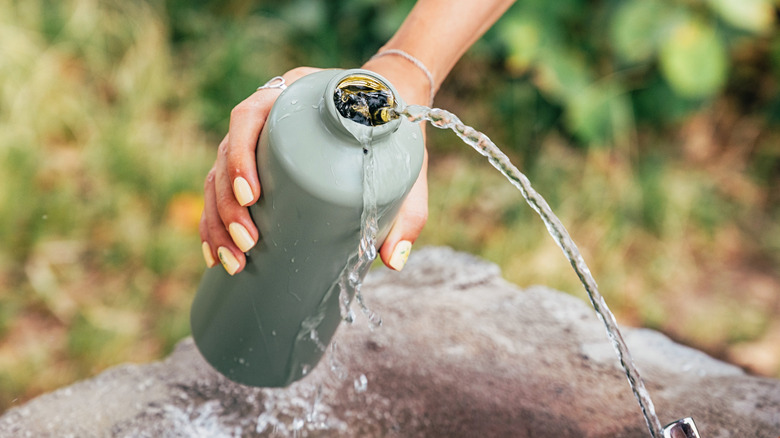 Water pouring from a reusable aluminum water bottle