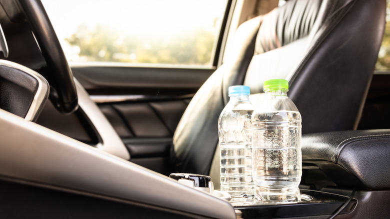 Two water bottles in the sun in the holders inside a car