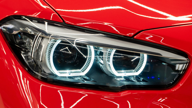 A modern red BMW's headlight assembly.