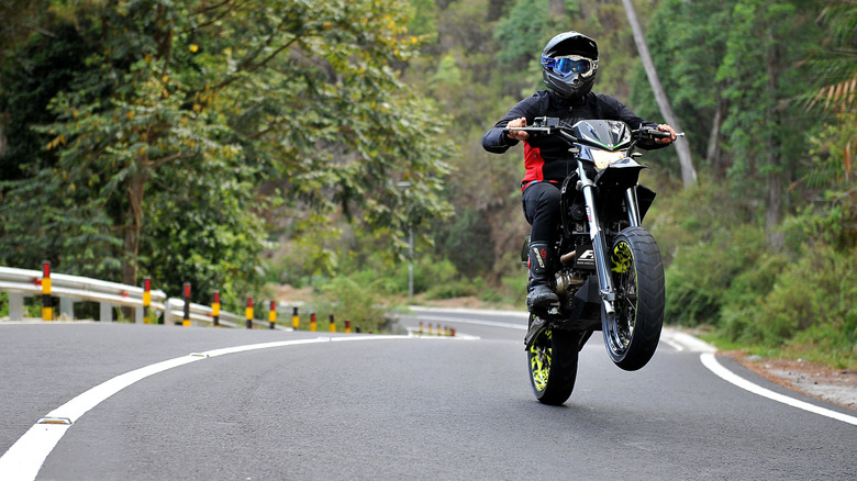 motorcyclist pulling a wheelie on the road