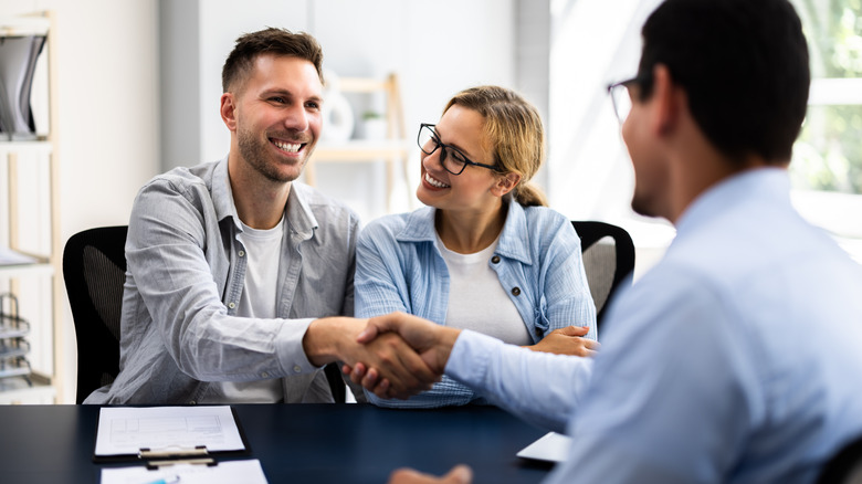 A couple sitting at a desk with a professional across from them and documents on the table.