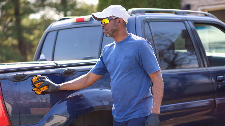 A man wiping down a pickup truck after washing