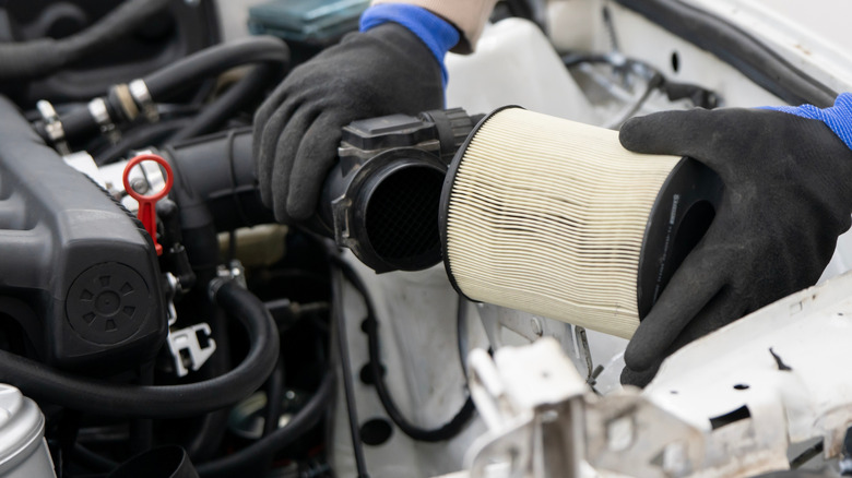 Person replacing stock air filter on a car.