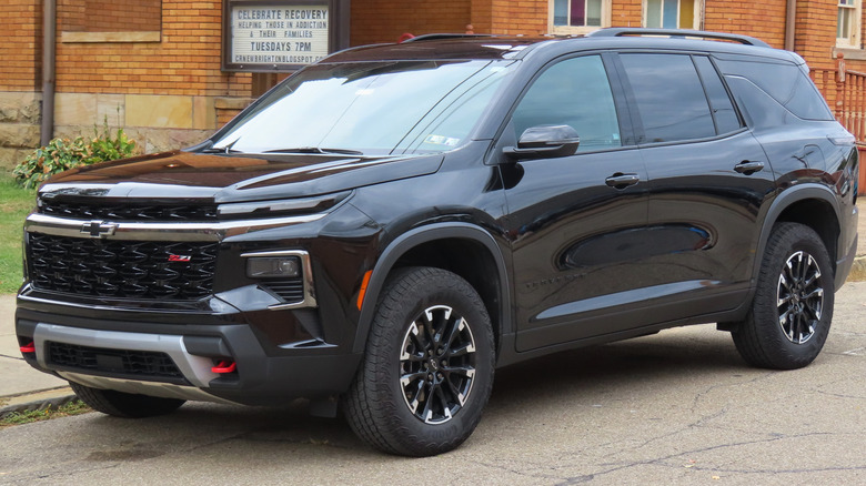 A black 2025 Chevrolet Traverse Z71 parked at the side of a road next to a building