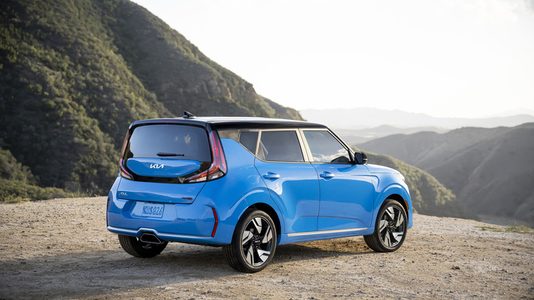 Rear 3/4 of 2024 Kia Soul in blue with black roof looking over mountains