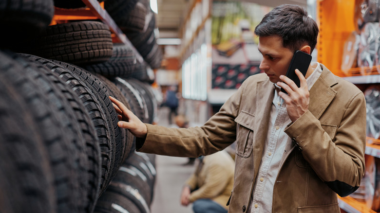A man talking on the phone while choosing new tires at the shop