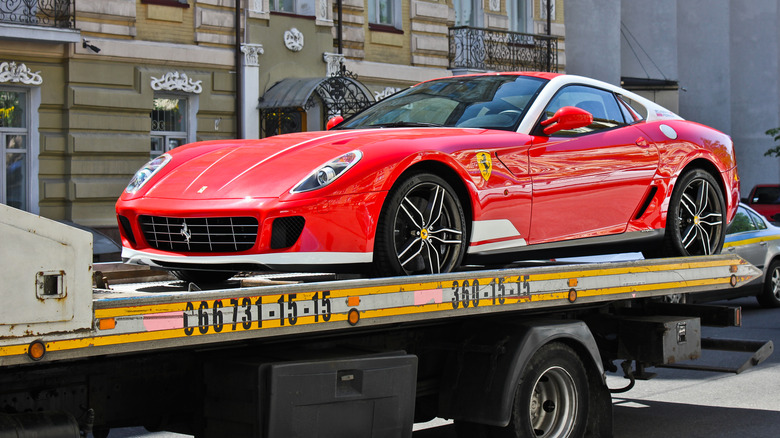 A red and white Ferrari 599 GTB 60F1 Alonso Edition on a flatbed tow truck.