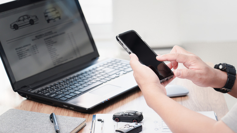 A buyer car shops on their phone and on a computer simultaneously.