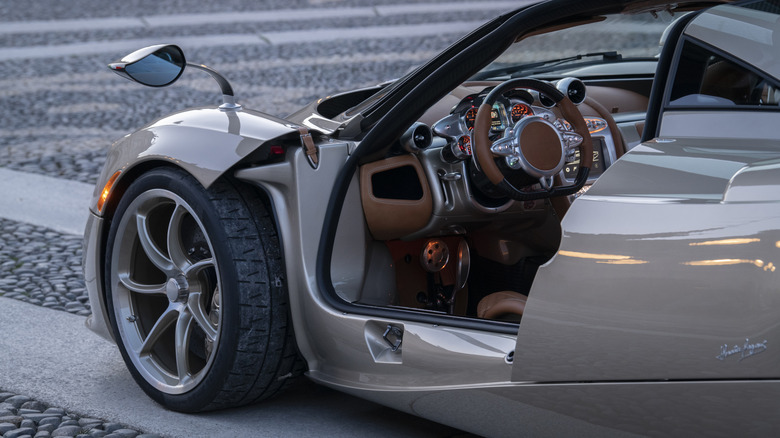 A side shot of a tan Pagani Codalunga with the door open, showing the cabin