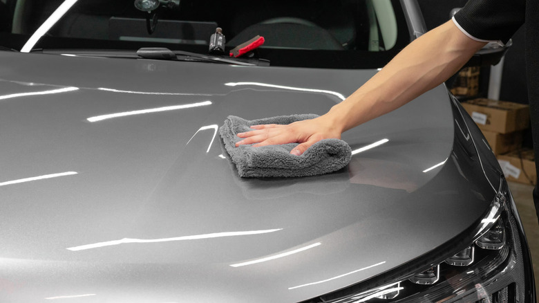 Professional detailer buffing nan hood of a grey sedan