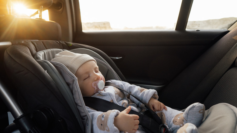 An infant in a rear-facing middle child seat.
