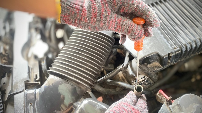 با دستان دستکش، میله مایع گیربکس خودرو را بررسی کنید