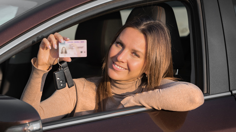 A young female holding up her driver's license.