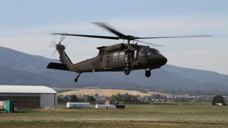 A Black Hawk helicopter hovering over a grassy field