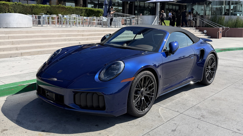 Front 3/4 view of a blue 2026 Porsche 911 Turbo S T-Hybrid cabriolet