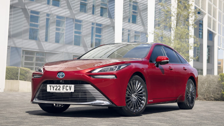 A red 2022 Toyota Mirai parked by a building