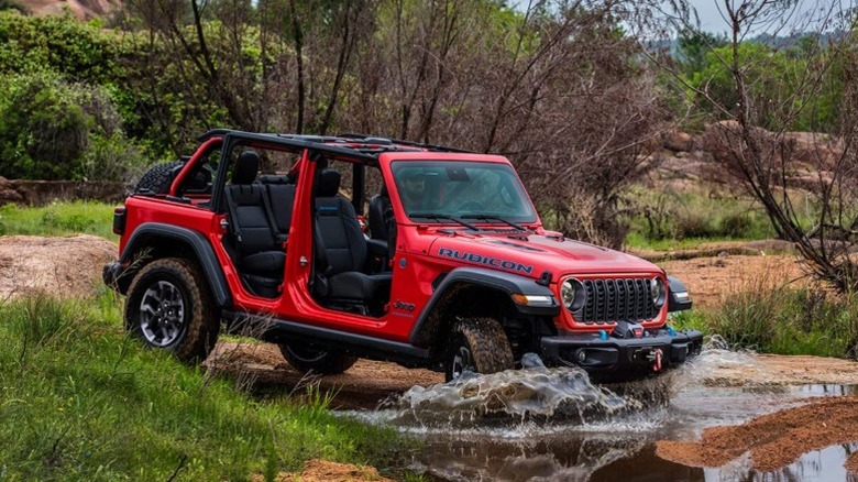 A red 2025 Jeep Wrangler driving through a pool of water