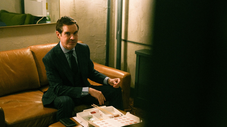 Jimmy Carr sitting on a couch eating sushi