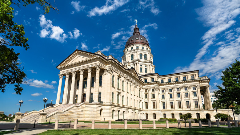 Kansas State Capitol in Topeka. Historic French Renaissance Revival architecture features a limestone facade with columns and a grand staircase under a blue sky
