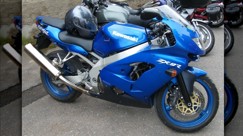 A metallic blue Kawasaki Ninja ZX-9R motorcycle with matching blue wheels parked outdoors.