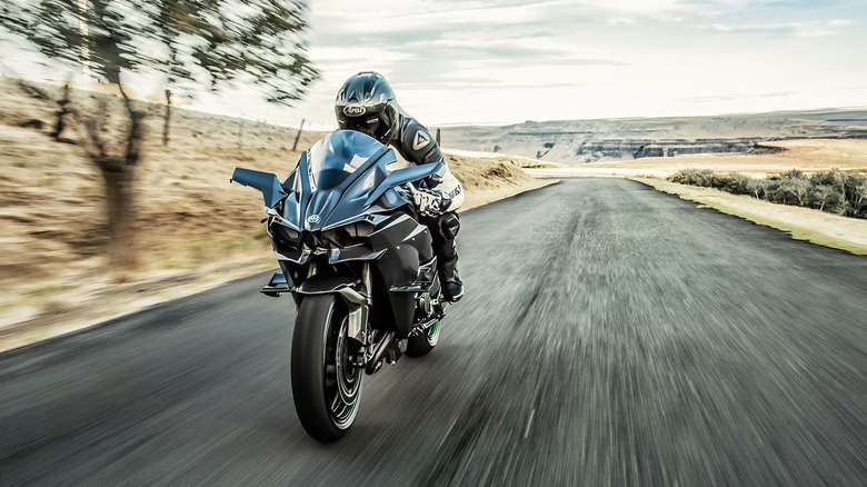 A frontal high-speed view of a dark Kawasaki Ninja H2R showing its aerodynamic carbon fiber fairing winglets.
