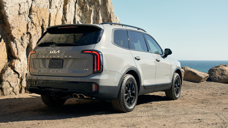 Rear 3/4 view of a 2024 Kia Telluride parked next to a cliff by the ocean