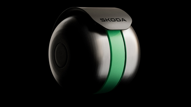 A close-up shot of the bell with a green stripe down the middle and a black flap that says &Scaron;koda in front of a black background