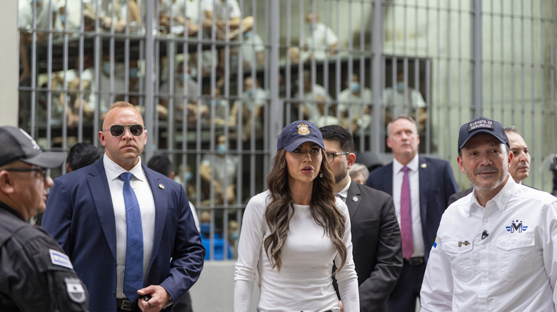 Kristi Noem stands with other government officials in front of CECOT prisoners