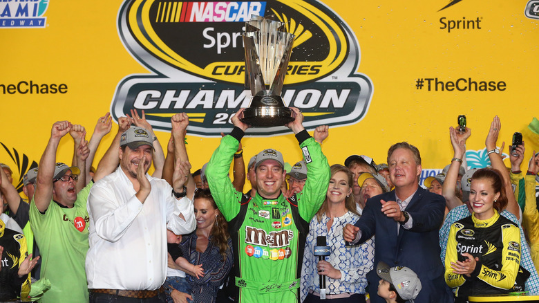 Kyle Busch, driver of the #18 M&M's Crispy Toyota, celebrates with the trophy in Victory Lane after winning the series championship and the NASCAR Sprint Cup Series Ford EcoBoost 400 at Homestead-Miami Speedway on November 22, 2015 in Homestead, Florida.