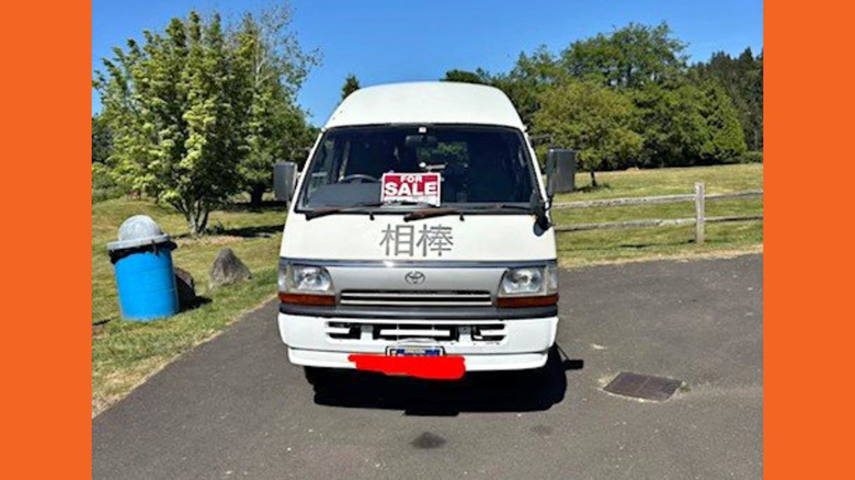A white Toyota HiAce with Japanese lettering on the front