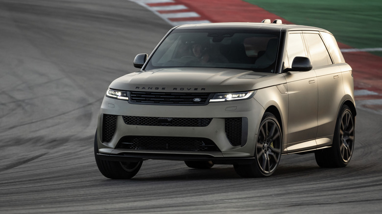 Front three-quarters shot of a matte gray Range Rover Sport SV driving around a corner on a race track in front of red and white curbs