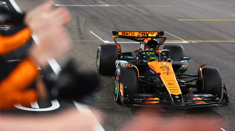 2025 F1 World Drivers Champion and Third placed Lando Norris of Great Britain driving the (4) McLaren MCL39 Mercedes passes his team celebrating on the pitwall during the F1 Grand Prix of Abu Dhabi at Yas Marina Circuit on December 07, 2025 in Abu Dhabi, United Arab Emirates.