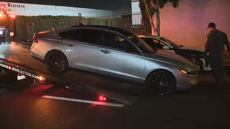 One of the 200 vehicles towed to be impounded from the street takeover, a silver sedan with tint and black wheels is placed on a flat towbed.