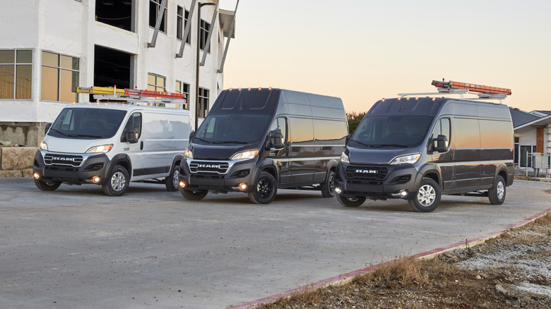 Front 3/4 view of three Ram ProMaster vans with low, medium, and high roof heights in a neighborhood under construction
