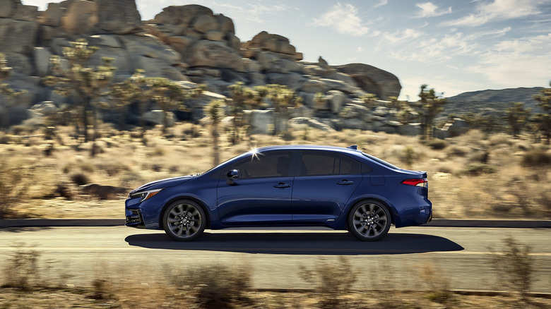 Profile of 2026 Toyota Corolla Hybrid driving on road through desert